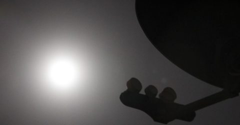 silhouette of satellite dish with sun behind it