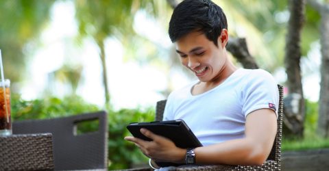 man laughing while using tablet