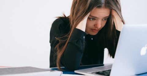 woman looking stressed and holding her head in her hands whileu