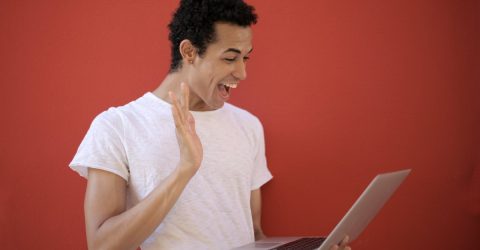 a man waving at a laptop screen