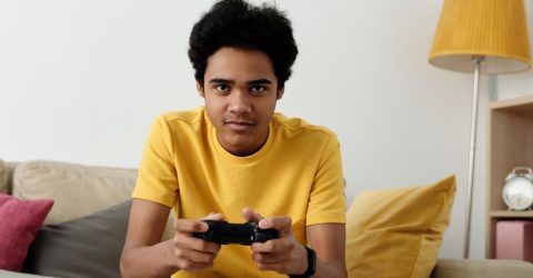 a boy in a yellow t shirt playing on a console
